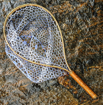 A bamboo fly fishing net lying on a rock in the water on the river in Western North Carolina. The rubber net basket is smooth and shiny and protects the fish for catch and release. The handle is flame cured for strength and durability and there is copper stitching and a copper keeper ring to attach your net keeper to.