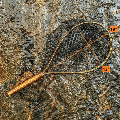 A bamboo fly fishing net lying on a rock in the water on the river in Western North Carolina. The rubber net basket is smooth and shiny and protects the fish for catch and release. The handle is flame cured for strength and durability and there is copper stitching and a copper keeper ring to attach your net keeper to.